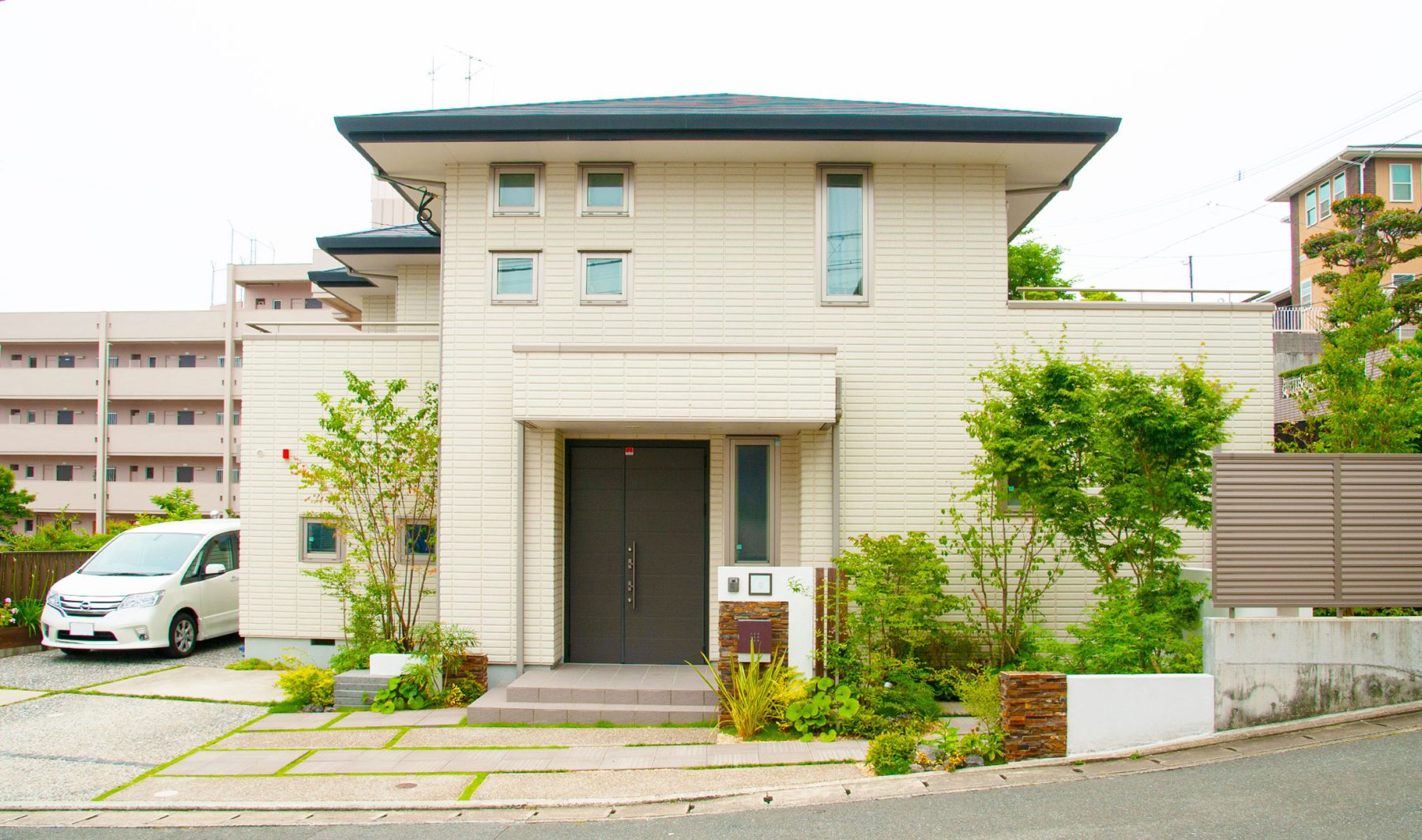 建物の白い外壁に緑の植栽が映える。