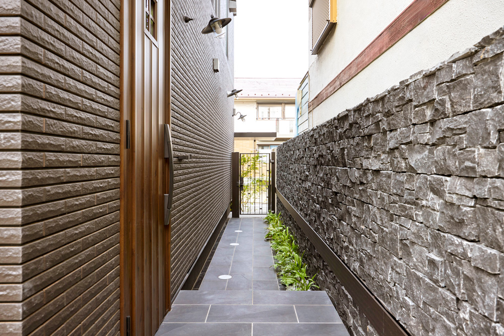 外壁と調和したグランドアートウォールが、 玄関までのアプローチに統一感を。